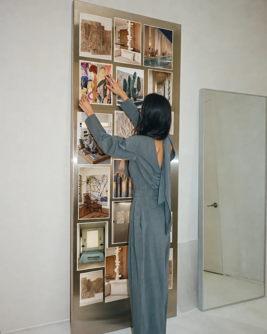 A woman arranging images and samples on a tall moodboard wall